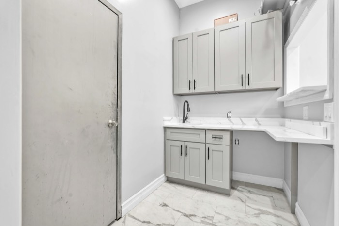 Prep pantry with quartz counter, sink and grey cabinetry