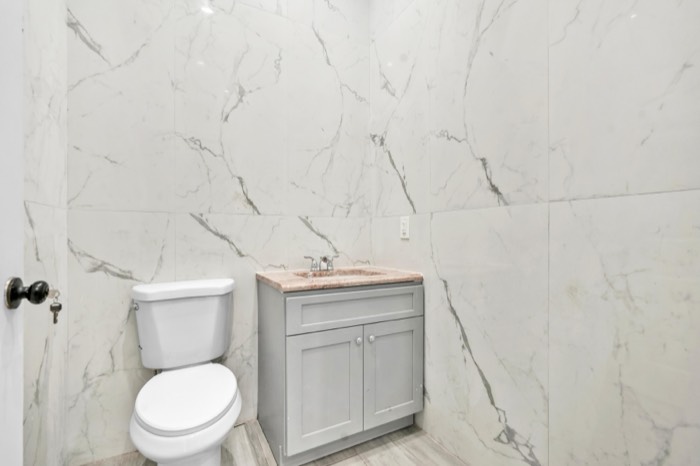 Private restroom fully clad in marble tile with a vanity